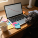 Laptop showing declining affiliate program performance graph with metrics dropping from month 1 to month 4, illustrated with colorful sticky notes on desk